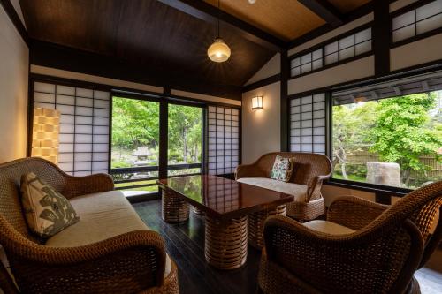 a room with chairs and a table and windows at 旅庵 川喜 in Omachi