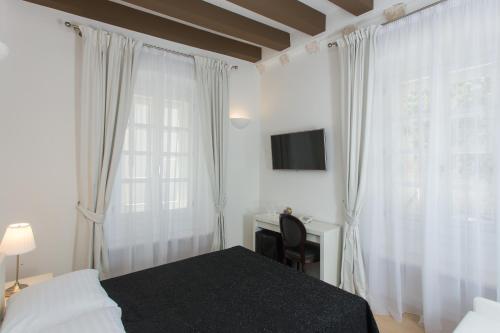 a bedroom with a bed and a desk and a window at Klarisa Palace Rooms in Dubrovnik