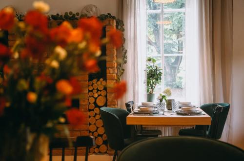 a table with chairs and a vase of flowers next to a window at Willa Marianna in Lądek-Zdrój