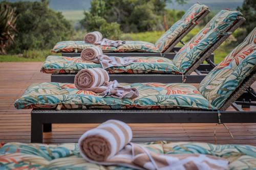 a row of chairs sitting on a wooden deck at Woodbury Manor - Amakhala Game Reserve in Sidbury