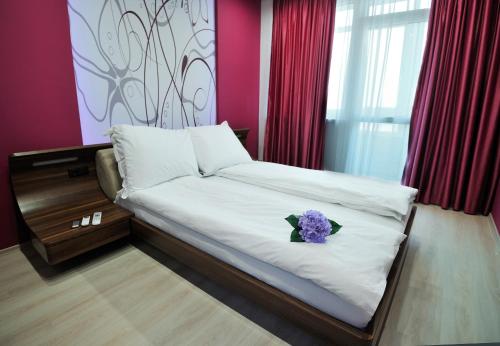ヴァルナ・シティにあるDelfin Apartmentのベッドルーム1室(紫の花が咲くベッド1台付)