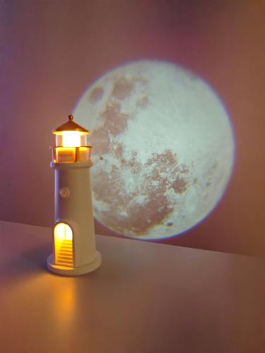 a lighthouse with the moon in the background at Atpūta pie Zilajiem kalniem in Ogre