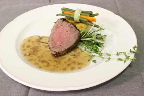 a plate of food with a piece of meat and vegetables at Hotel Rosalpina in Soraga