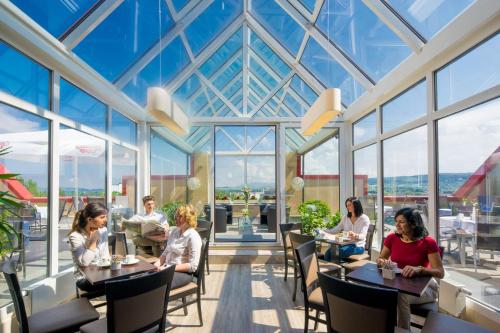 a group of people sitting at tables in a restaurant at Maximilian Hotel & Apartments Weil am Rhein / Basel in Weil am Rhein