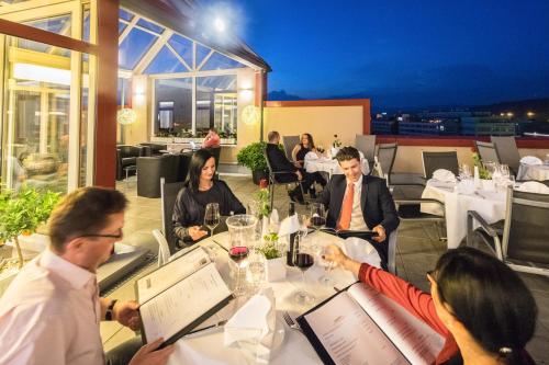 a group of people sitting at a table in a restaurant at Maximilian Hotel & Apartments Weil am Rhein / Basel in Weil am Rhein