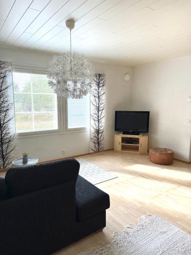 a living room with a couch and a flat screen tv at Polar Night Wooden House with Sauna in Sodankylä