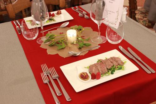 a table with two plates of food on a red table cloth at Hotel Rosalpina in Soraga