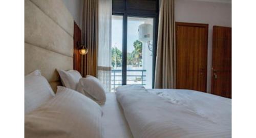 una camera da letto con un letto con cuscini bianchi e una finestra di Tranquil Point Residence a Kigali
