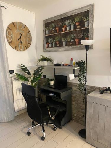 an office with a desk and a chair and a clock at Grazioso monolocale con giardino in Pregnana Milanese