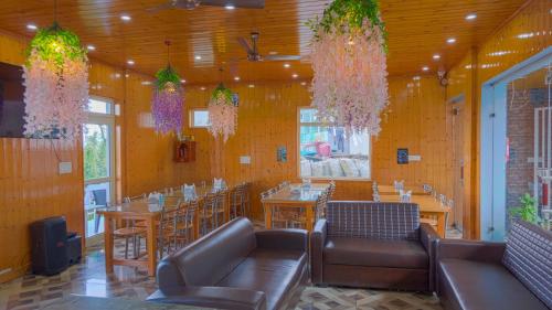 a restaurant with tables and chairs and chandeliers at Pacific Inn Mussoorie in Mussoorie