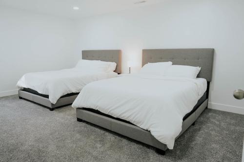 two beds in a room with white sheets and pillows at 5040 Sqft l Sleeps 25 l Near Ski & Downtown SLC in West Jordan