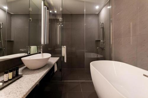 a bathroom with a large white tub and a sink at Top Cloud Hotel Iksan in Iksan