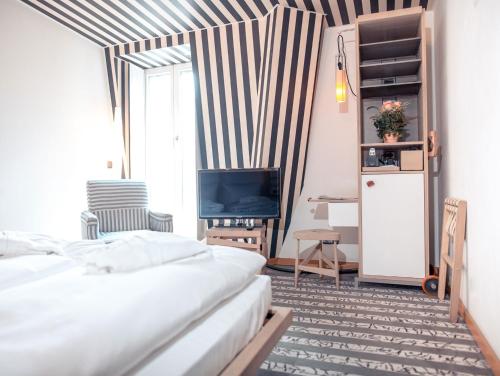 a bedroom with a bed and a dresser at Hotel Bleibtreu Berlin by Golden Tulip in Berlin