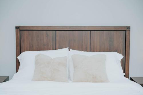 a bed with white pillows and a wooden headboard at 5040 Sqft l Sleeps 25 l Near Ski & Downtown SLC in West Jordan