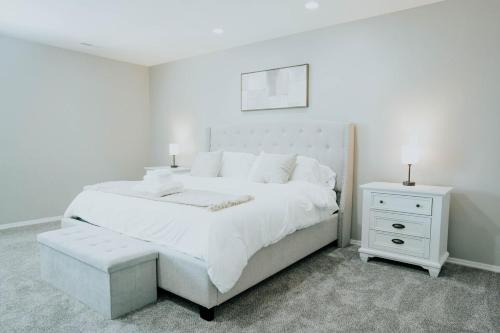 a white bedroom with a large bed and a nightstand at 5040 Sqft l Sleeps 25 l Near Ski & Downtown SLC in West Jordan