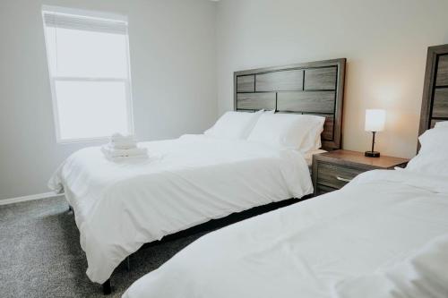 two white beds in a bedroom with a window at 5040 Sqft l Sleeps 25 l Near Ski & Downtown SLC in West Jordan