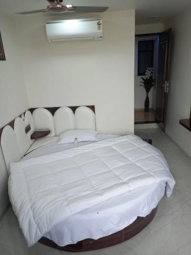 a bedroom with a large white bed with a white comforter at Hotel Rest in Ahmedabad