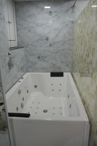 a white bath tub in a bathroom with marble walls at Hotel Rest in Ahmedabad