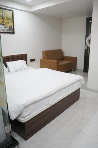 a bedroom with a large bed and a chair at Hotel Rest in Ahmedabad