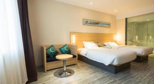 a hotel room with two beds and a chair at City Comfort Inn Wuhan High Speed Railway Station in Wuhan