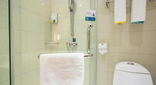 a bathroom with a shower with a toilet and a towel at City Comfort Inn Wuhan High Speed Railway Station in Wuhan
