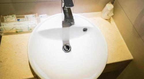 a white bathroom sink with a faucet on it at City Comfort Inn Wuhan High Speed Railway Station in Wuhan
