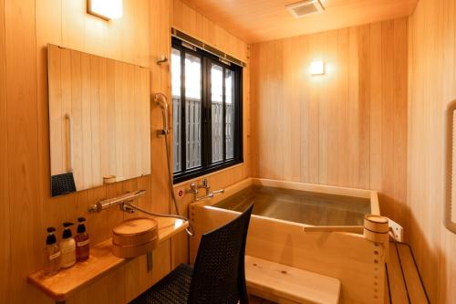 a bathroom with a tub and a sink and a window at 旅庵 川喜 in Omachi