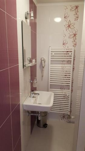 a bathroom with a white sink and a mirror at Penzión Galéria in Bojnice