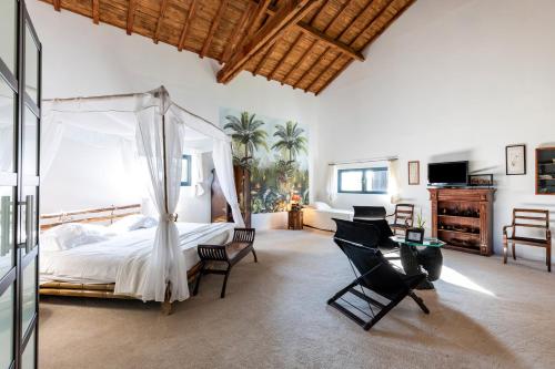 a bedroom with a bed and chairs in a room at Le Palmier Exotique in Bazas
