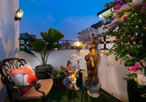 a balcony with a statue and a table and flowers at Hanoi de Garden Boutique Hotel & Spa in Hanoi