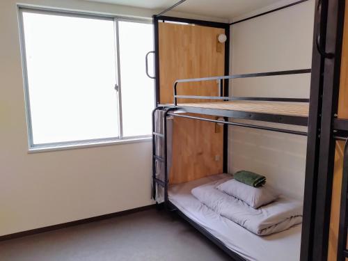 a bunk bed in a room with a window at TONARINO Hostel for Backpackers in Kobe