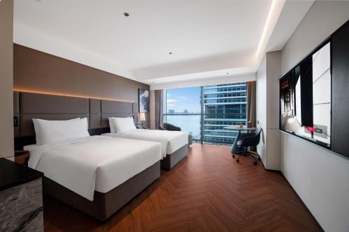 two beds in a hotel room with a large window at Intercity Hotel Shantou CHJ in Shantou