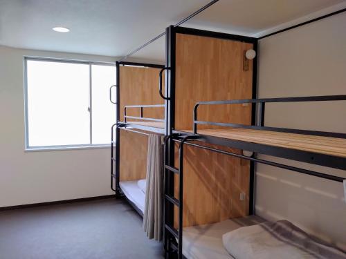 a room with bunk beds with a window at TONARINO Hostel for Backpackers in Kobe