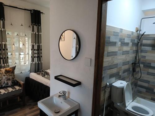 a bathroom with a sink and a toilet and a mirror at Escape Hole in Diani Beach