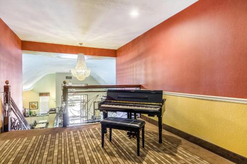 a piano in a living room with a staircase at Quality Suites North Houston - Spring in Houston