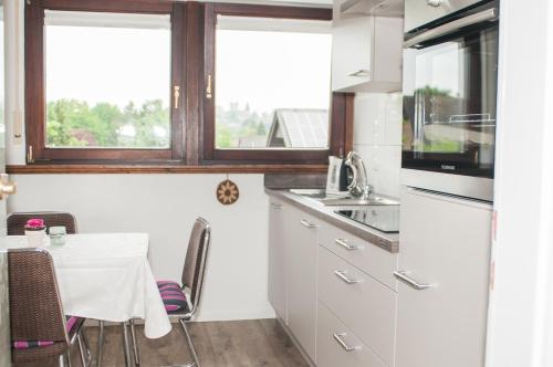 a kitchen with white cabinets and a table with chairs at Aaltine 2 in Bad Bentheim