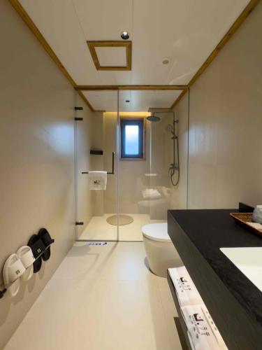a bathroom with a toilet and a glass shower at M Country Road 山行野奢影院温泉民宿 in Dujiangyan