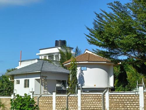 a white house behind a fence at Escape Hole in Diani Beach