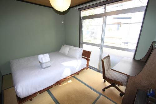 Un dormitorio con una cama y una silla y una ventana. en 抹茶庵伏見京都 Matcha-An Fushimi Kyoto, en Kioto