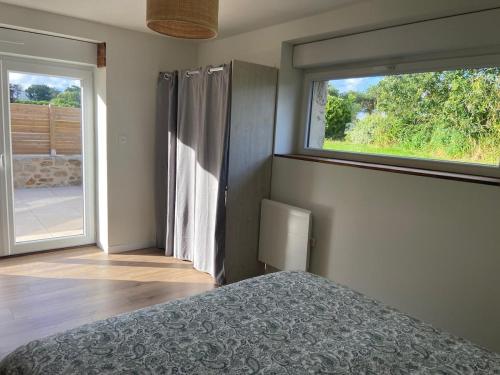 a bedroom with a bed and a large window at Petite maison à la campagne in Ploudaniel
