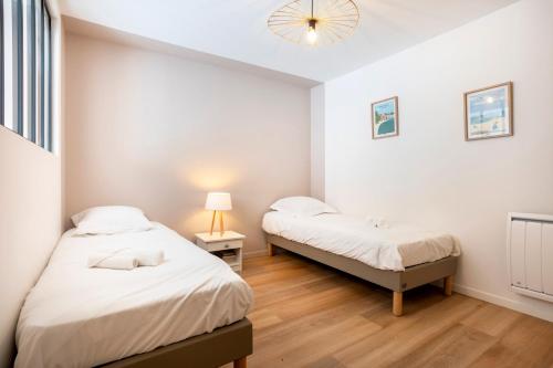 a bedroom with two beds and a lamp in it at L’Escale – Tout à pied à Ste-Marine in Combrit