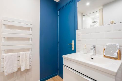 a bathroom with a white sink and a blue door at L’Escale – Tout à pied à Ste-Marine in Combrit