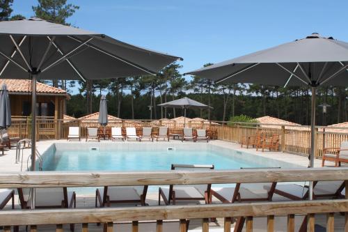 a swimming pool with tables and chairs and umbrellas at Domaine du Ferret Restaurant & Spa in Cap-Ferret