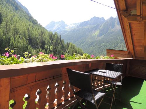 a table and chairs on a balcony with a view of mountains at Pension Winnebach in Längenfeld