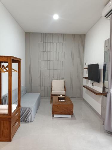 a bedroom with a bed and a chair and a tv at Rauda Living Space Syariah in Pasuruan