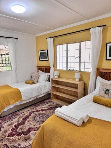 - 2 lits dans une chambre dotée de murs et de fenêtres jaunes dans l'établissement Fish Eagle Cottage, 