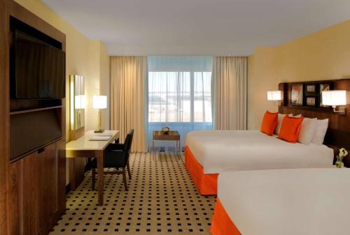 a hotel room with two beds and a desk and a television at Radisson Blu Mall of America in Bloomington