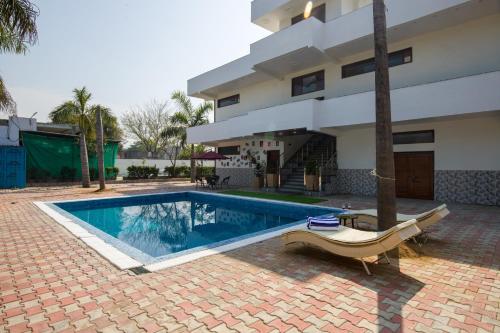 a swimming pool in front of a house at ELIVAAS Ivory estate 5 BHK Farm with Pvt Pool, Gazebos & Lounge Area in Manjhāoli