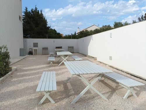 a group of picnic tables next to a white wall at Dara Holiday Apartments in Marsala