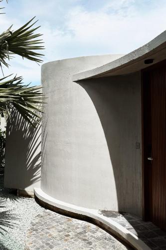 a concrete building with a palm tree in front of it at Serene Vita Retreat in Phumĭ Ŏng Char